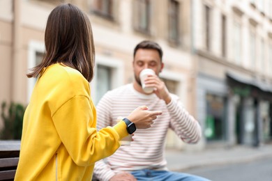 Photo of Coffee to go. Couple with paper cups of drinks on city street, selective focus. Space for text