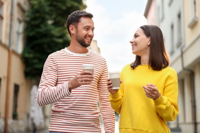 Photo of Coffee to go. Couple with paper cups of drinks walking on city street, low angle view