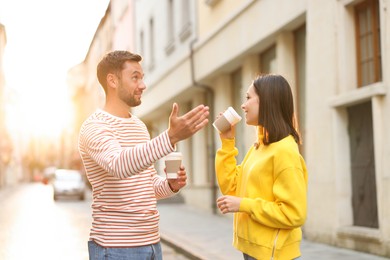 Photo of Coffee to go. Couple with paper cups of drinks on city street