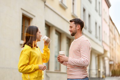 Photo of Coffee to go. Couple with paper cups of drinks on city street