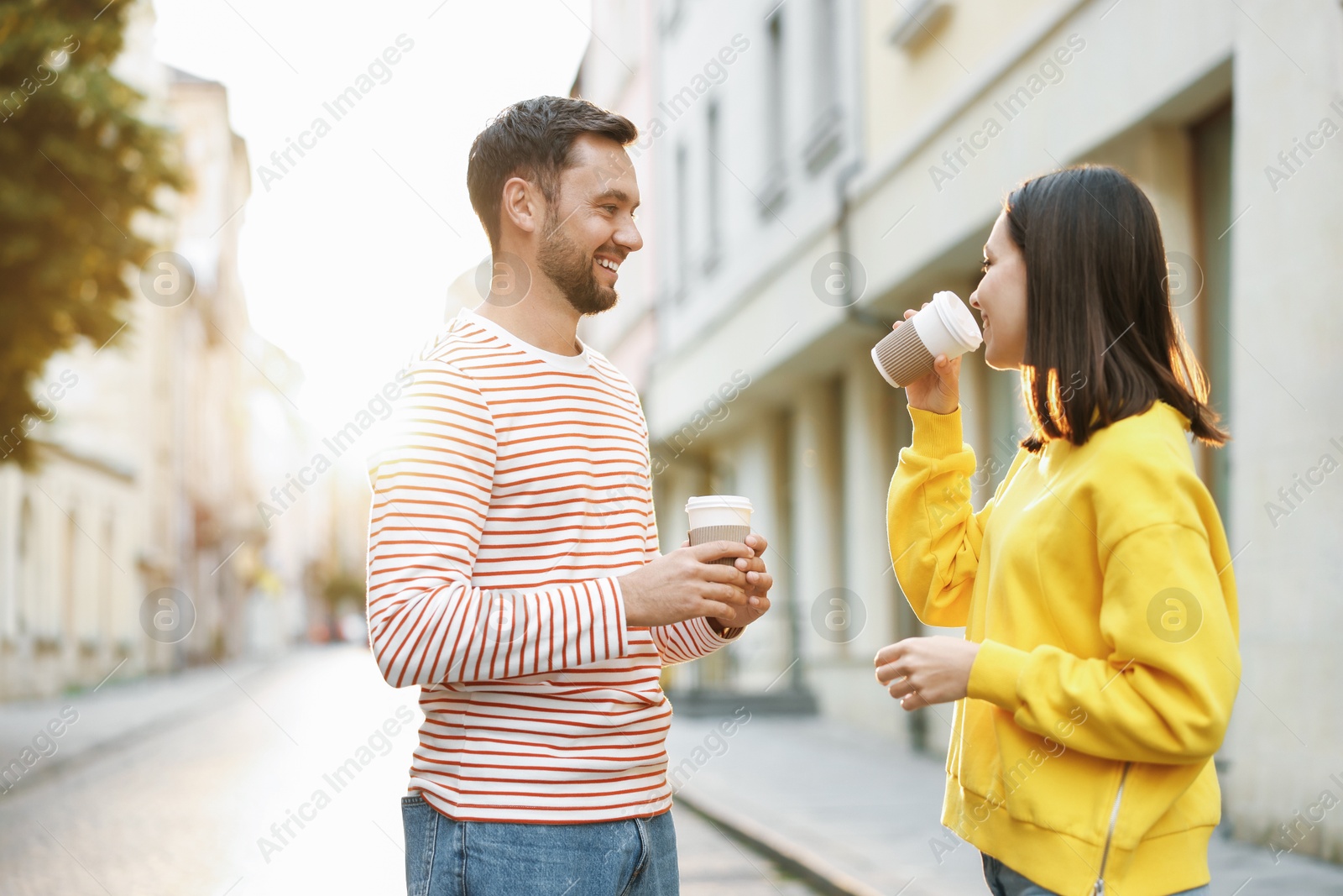 Photo of Coffee to go. Couple with paper cups of drinks on city street