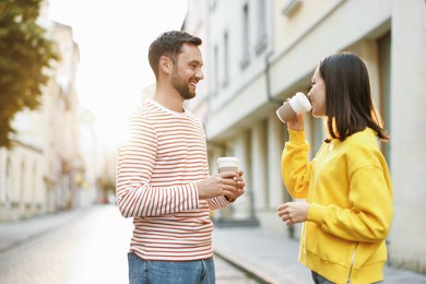 Photo of Coffee to go. Couple with paper cups of drinks on city street