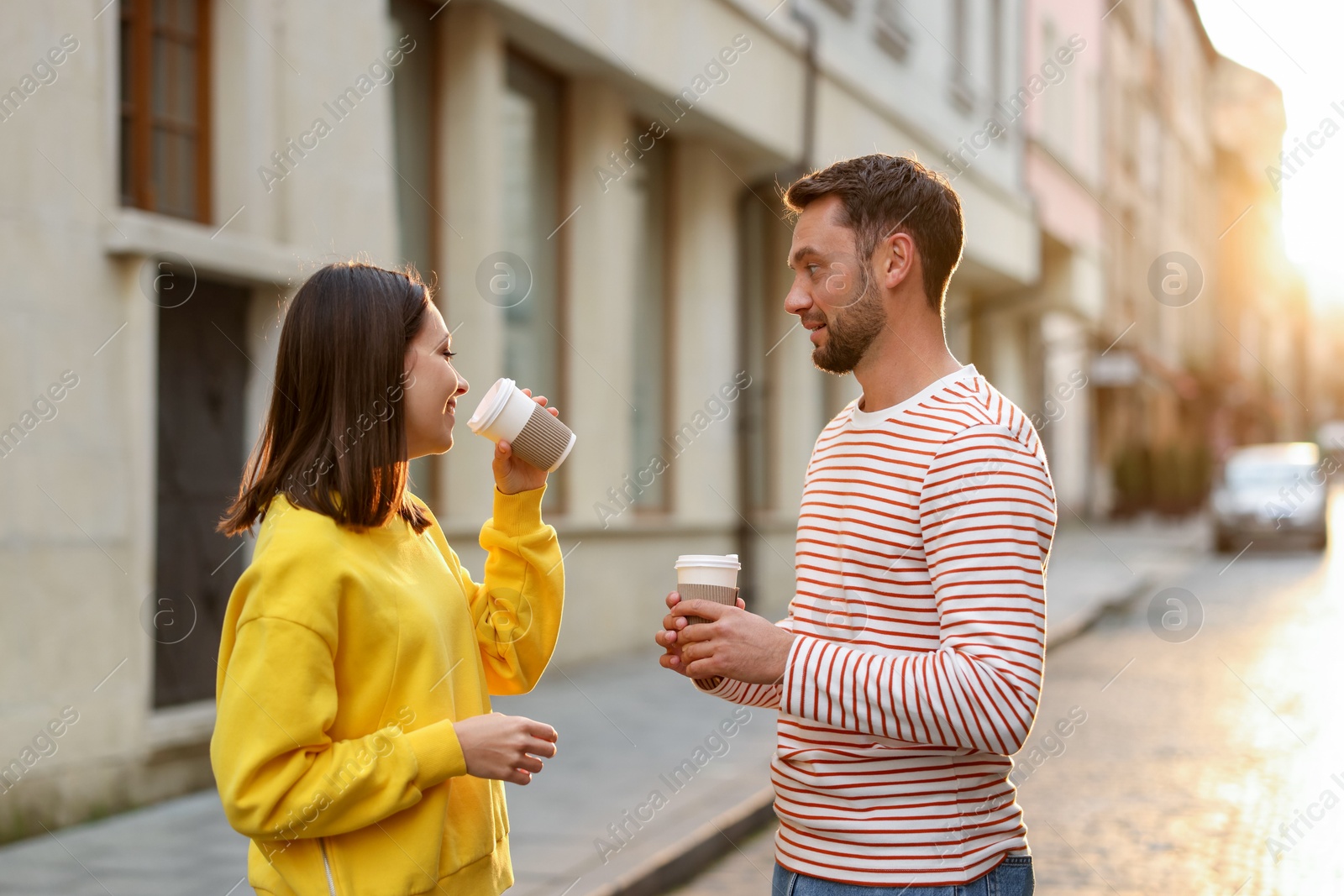 Photo of Coffee to go. Couple with paper cups of drinks on city street