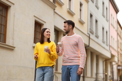 Photo of Coffee to go. Couple with paper cups of drinks walking on city street, low angle view