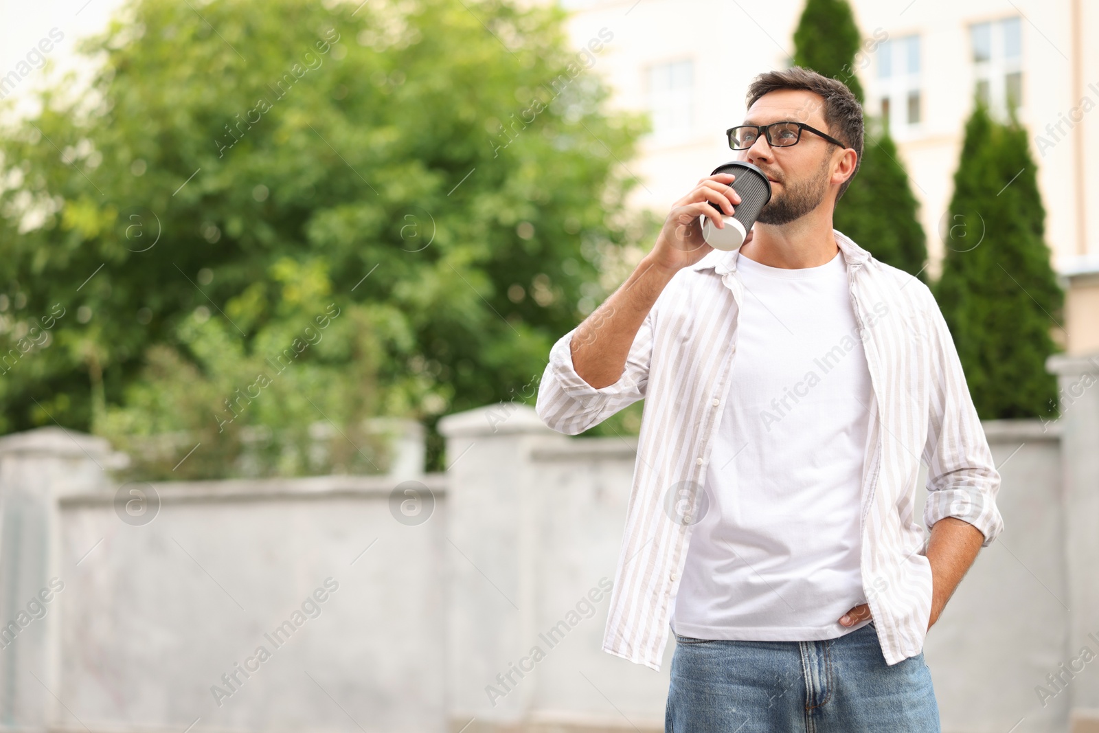 Photo of Coffee to go. Man with paper cup of drink outdoors, space for text
