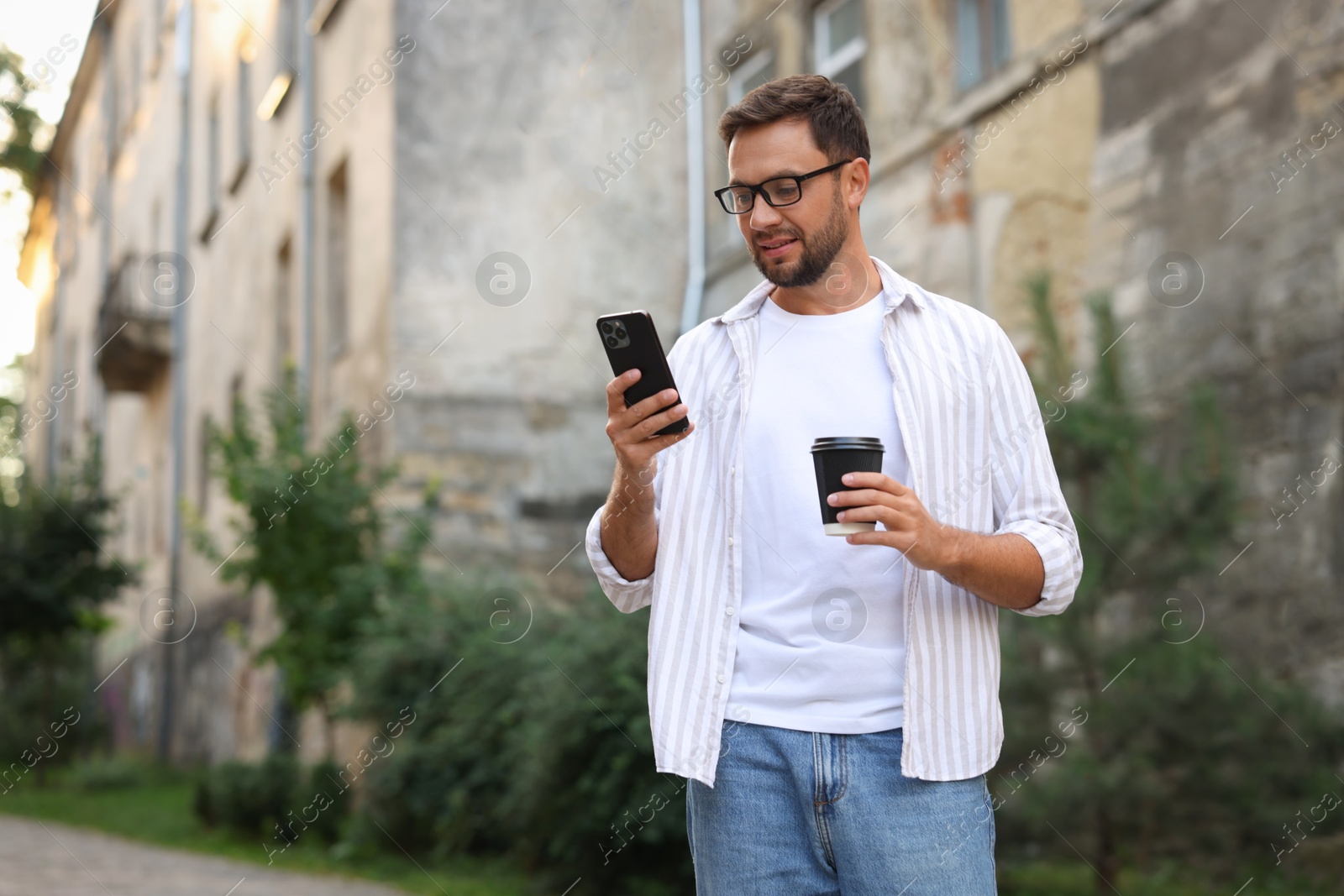 Photo of Coffee to go. Man with paper cup of drink and smartphone outdoors, space for text