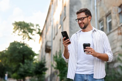 Photo of Coffee to go. Man with paper cup of drink and smartphone outdoors, space for text