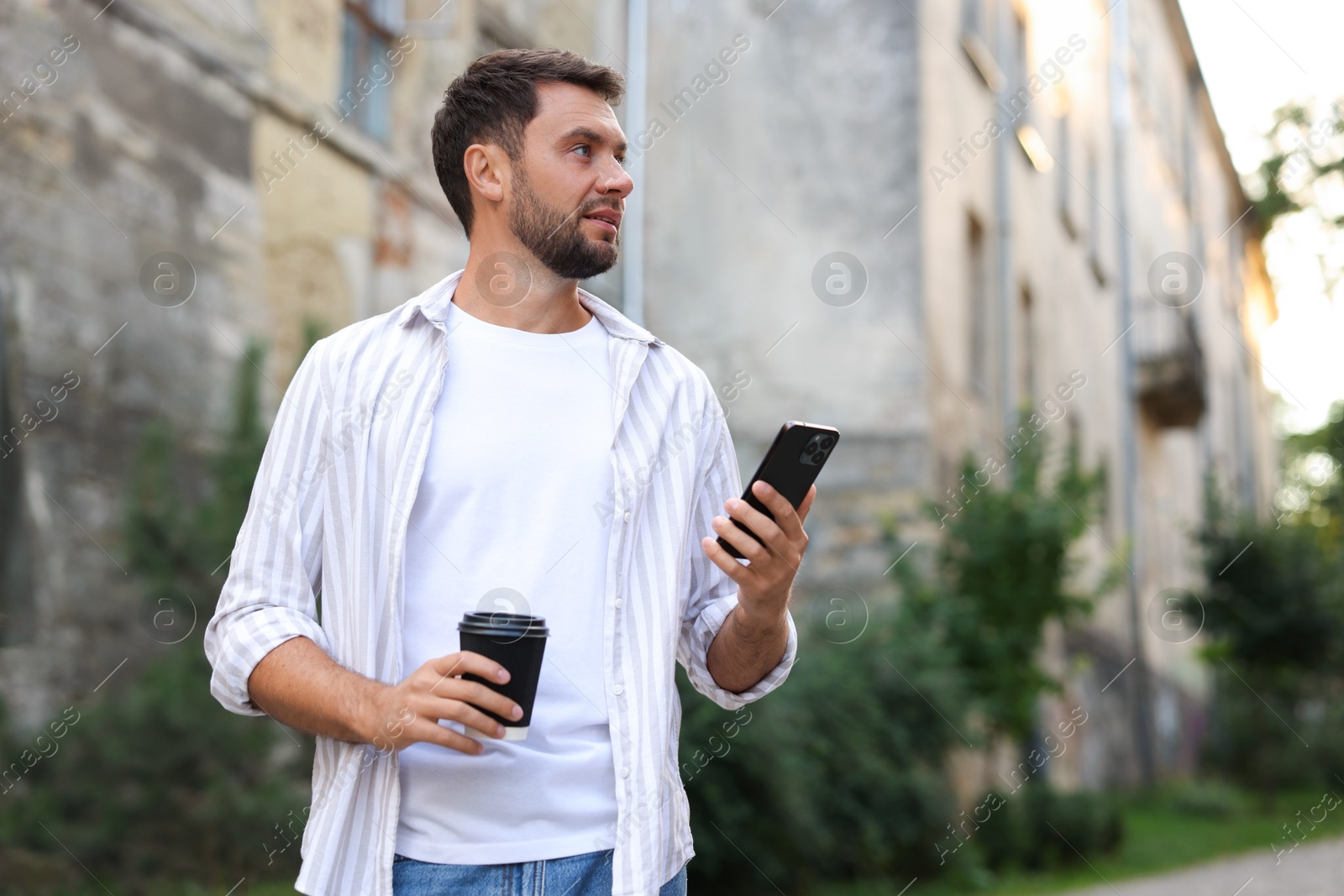 Photo of Coffee to go. Man with paper cup of drink and smartphone outdoors, space for text