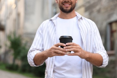 Photo of Coffee to go. Man with paper cup of drink outdoors, closeup