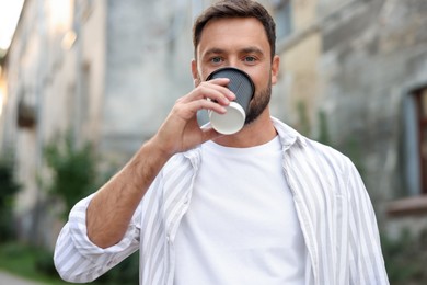 Photo of Coffee to go. Man with paper cup of drink outdoors