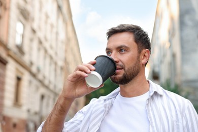 Photo of Coffee to go. Man with paper cup of drink outdoors, space for text