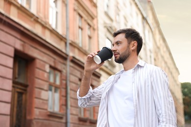 Photo of Coffee to go. Man with paper cup of drink outdoors, low angle view. Space for text