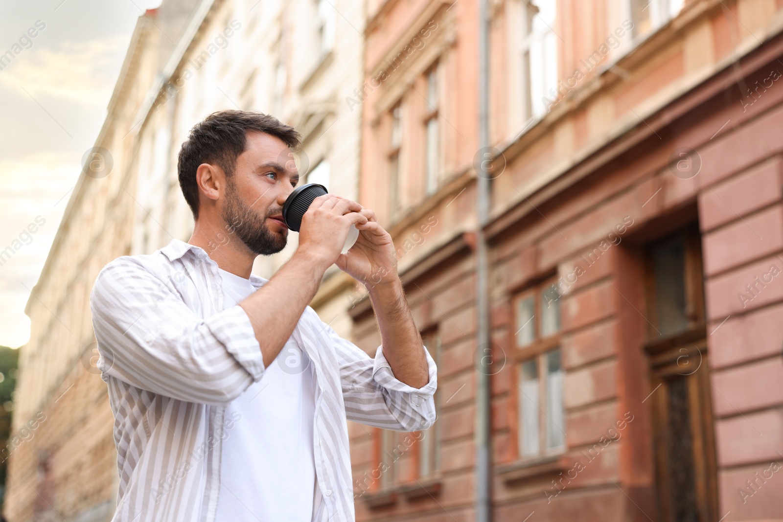 Coffee to go. Man with paper cup of drink outdoors, low angle view. Space for text Photo of Coffee to go. Man with paper cup of drink outdoors, low angle view. Space for text