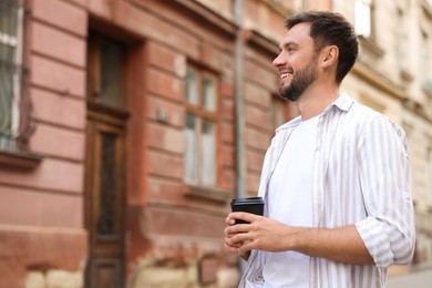 Photo of Coffee to go. Man with paper cup of drink outdoors, space for text