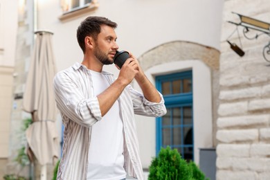 Photo of Coffee to go. Man with paper cup of drink talking on smartphone outdoors, space for text