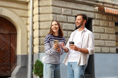 Photo of Coffee to go. Couple with paper cup of drink and smartphone outdoors, space for text