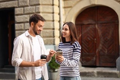 Photo of Coffee to go. Couple with paper cups of drinks outdoors, space for text