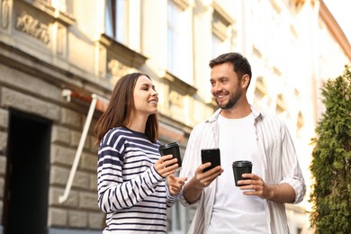 Photo of Coffee to go. Couple with paper cups of drinks and smartphone outdoors