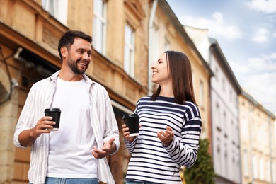 Photo of Coffee to go. Couple with paper cups of drinks walking on city street, low angle view