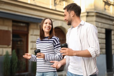 Photo of Coffee to go. Couple with paper cups of drinks walking on city street
