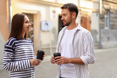 Photo of Coffee to go. Couple with paper cups of drinks walking on city street