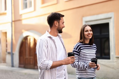 Photo of Coffee to go. Couple with paper cups of drinks walking on city street, space for text