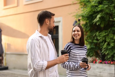 Photo of Coffee to go. Couple with paper cups of drinks walking on city street