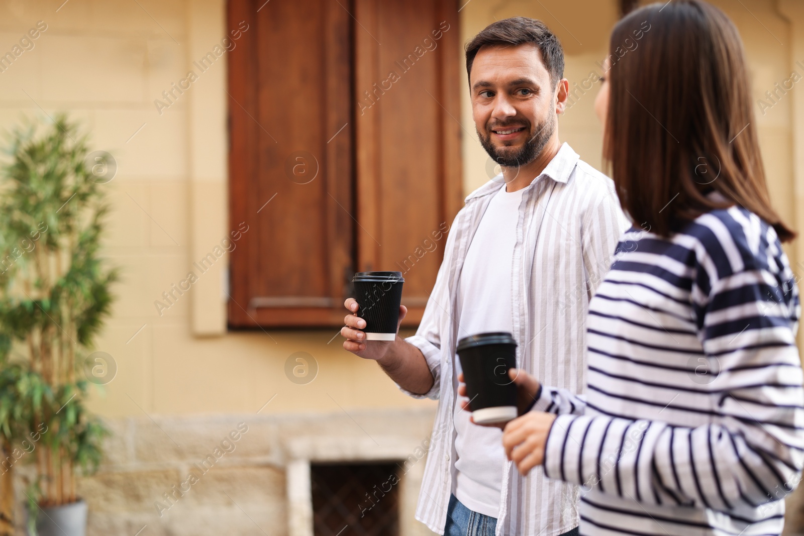 Photo of Coffee to go. Couple with paper cups of drinks walking on city street, space for text