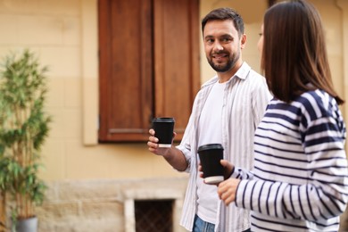 Photo of Coffee to go. Couple with paper cups of drinks walking on city street, space for text