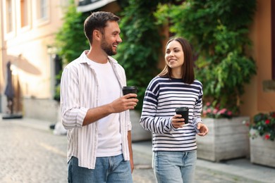 Photo of Coffee to go. Couple with paper cups of drinks walking on city street