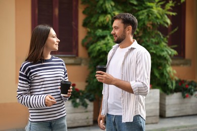 Photo of Coffee to go. Couple with paper cups of drinks walking on city street
