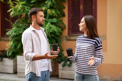 Photo of Coffee to go. Couple with paper cups of drinks walking on city street