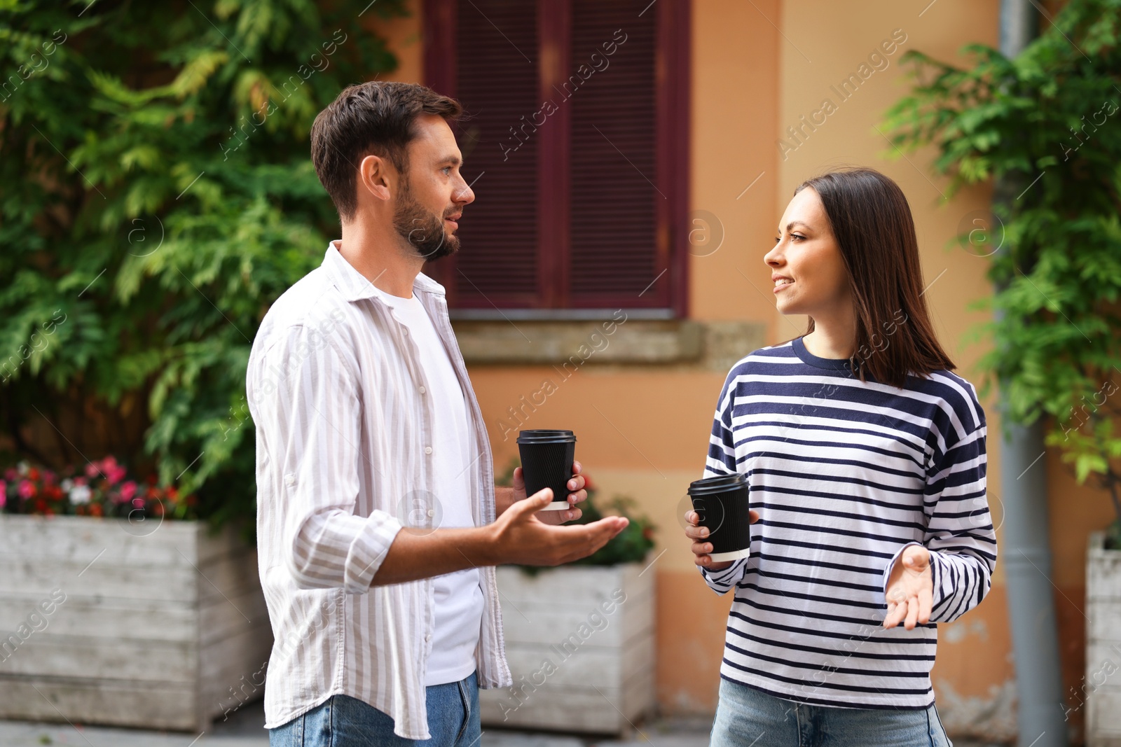 Photo of Coffee to go. Couple with paper cups of drinks walking on city street