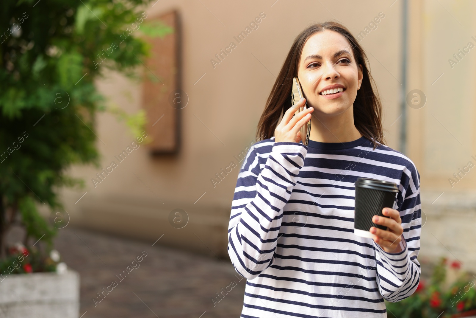 Coffee to go. Woman with paper cup of drink talking on smartphone outdoors, space for text Photo of Coffee to go. Woman with paper cup of drink talking on smartphone outdoors, space for text