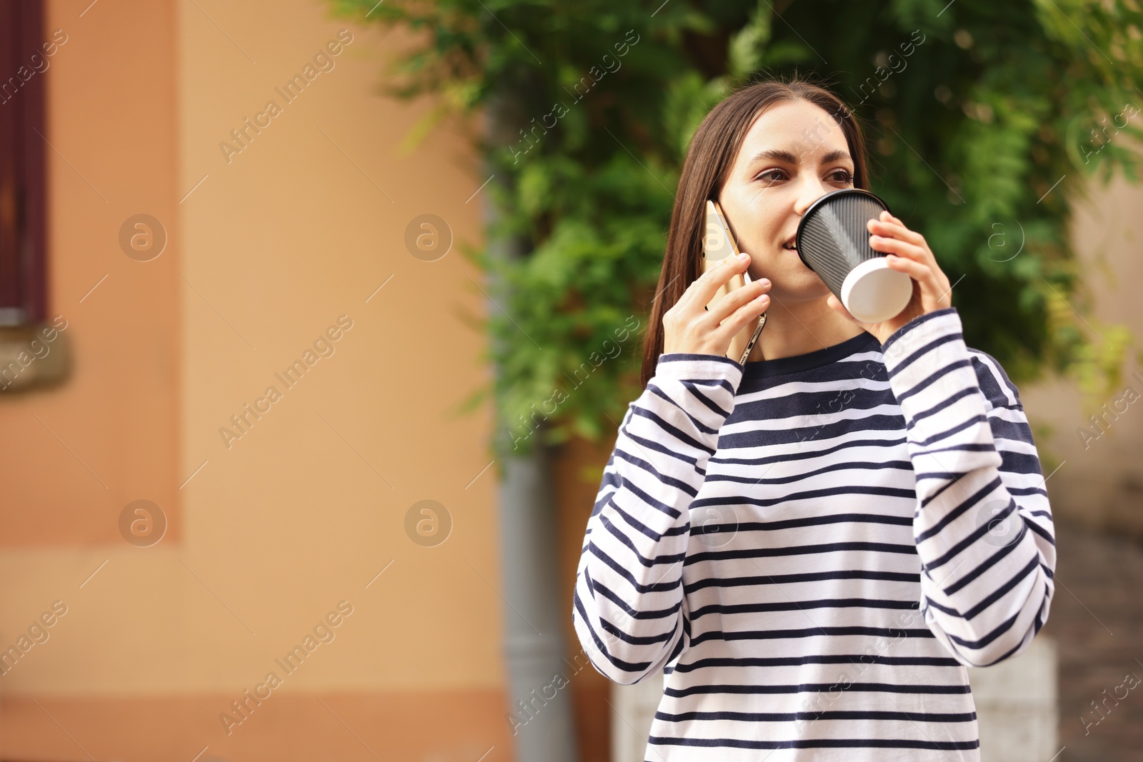 Coffee to go. Woman with paper cup of drink talking on smartphone outdoors, space for text Photo of Coffee to go. Woman with paper cup of drink talking on smartphone outdoors, space for text