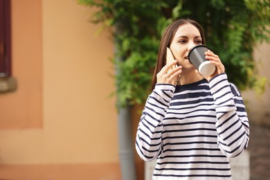 Photo of Coffee to go. Woman with paper cup of drink talking on smartphone outdoors, space for text