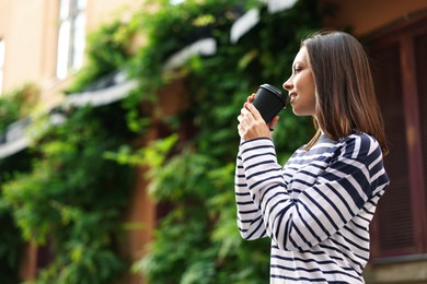 Photo of Coffee to go. Woman with paper cup of drink outdoors, low angle view. Space for text