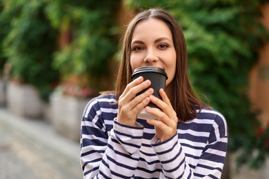 Photo of Coffee to go. Woman with paper cup of drink outdoors, space for text