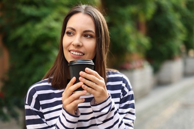 Photo of Coffee to go. Woman with paper cup of drink outdoors, space for text