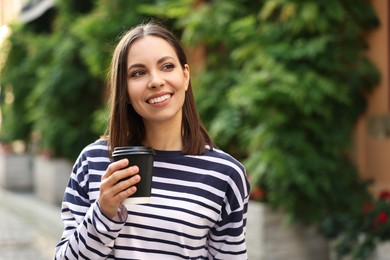Photo of Coffee to go. Woman with paper cup of drink outdoors, space for text