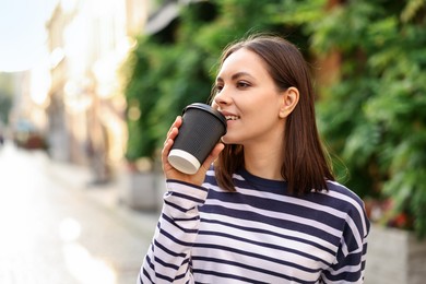 Photo of Coffee to go. Woman with paper cup of drink outdoors, space for text