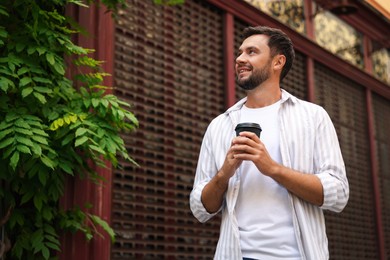 Photo of Coffee to go. Man with paper cup of drink outdoors, low angle view. Space for text
