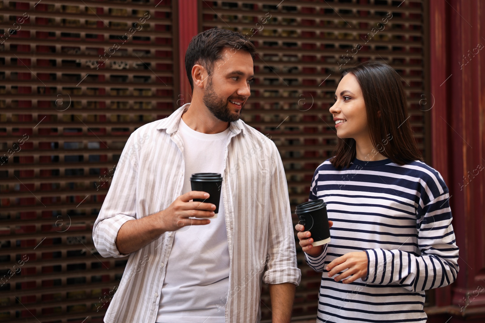 Photo of Coffee to go. Couple with paper cups of drinks outdoors