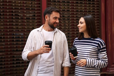 Photo of Coffee to go. Couple with paper cups of drinks outdoors