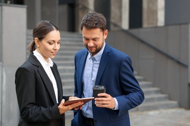 Photo of Coffee to go. Man with paper cup of drink and his business partner during meeting outdoors, space for text