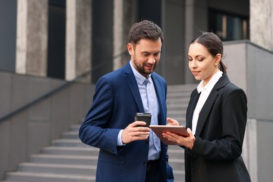 Photo of Coffee to go. Man with paper cup of drink and his business partner during meeting outdoors, space for text