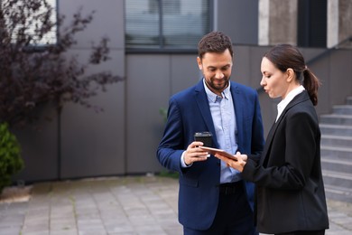 Photo of Coffee to go. Man with paper cup of drink and his business partner during meeting outdoors, space for text