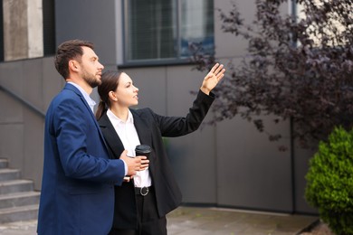 Photo of Coffee to go. Businesspeople with paper cups of drinks near building outdoors, space for text
