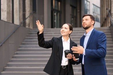Photo of Coffee to go. Businesspeople with paper cups of drinks near building outdoors, space for text