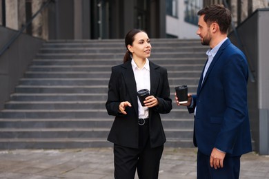 Photo of Coffee to go. Businesspeople with paper cups of drinks near building outdoors, space for text